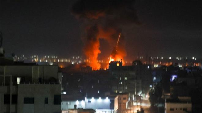 Explosions light-up the night sky above buildings in Gaza City as Israeli forces shell the Palestinian enclave,