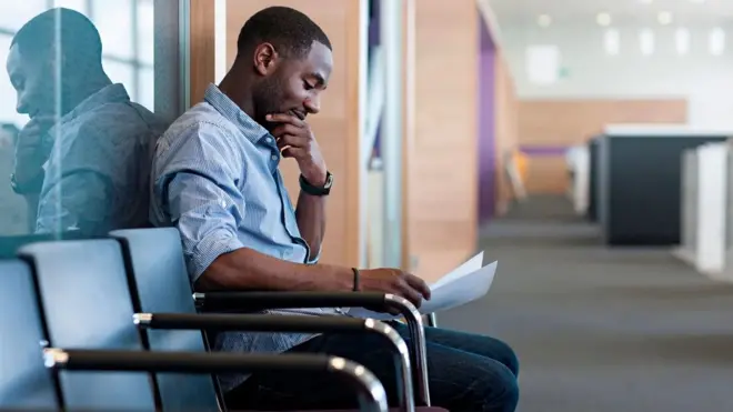 Un homme en sourire assis près de la porte d'un bureau