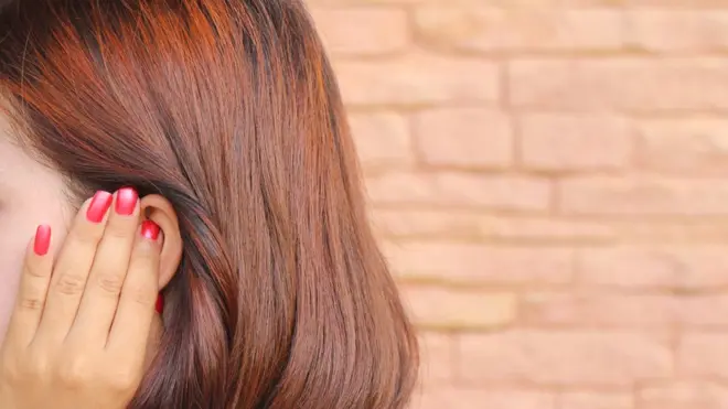 一名女人把手放在耳朵上