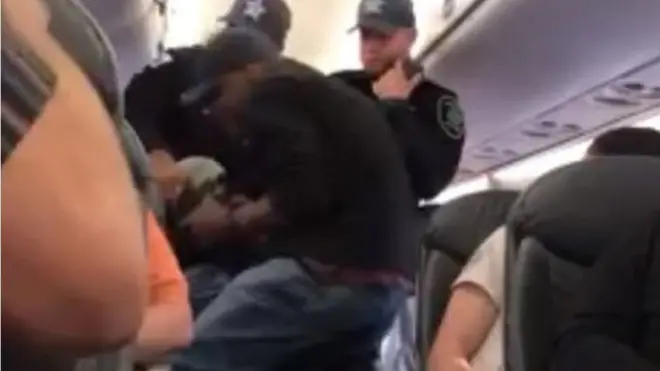 Penumpang yang diyakini sebagai seorang dokter ditarik oleh petugas keamanan.