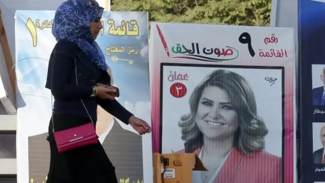 Woman walks past campaign poster in Amman (15/09/16)