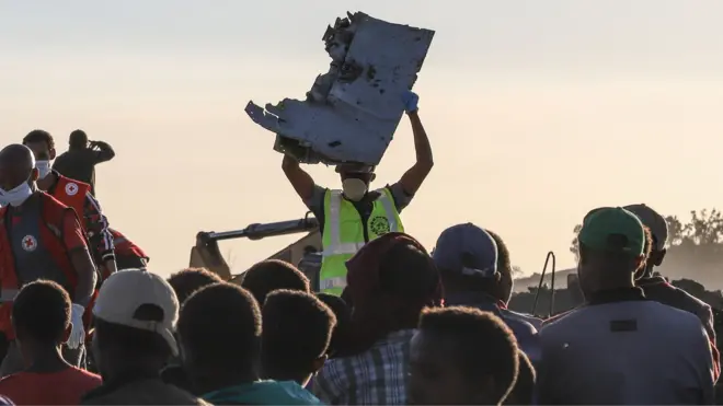 A man carries a piece of debris on his head at the crash site of a Nairobi-bound Ethiopian Airlines flight near Bishoftu