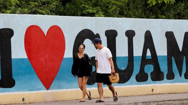 Turistas caminan por delante de un cartel que dice, en inglés, "yo amo Guam".