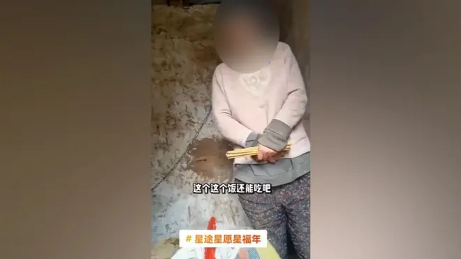 لقطة من الفيديو تُظهر المرأة مغلولة العنق في كوخ ريفي