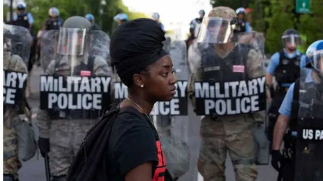 Black woman in front of police in riot gear