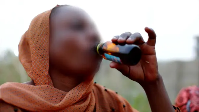 A woman drinking cough syrup