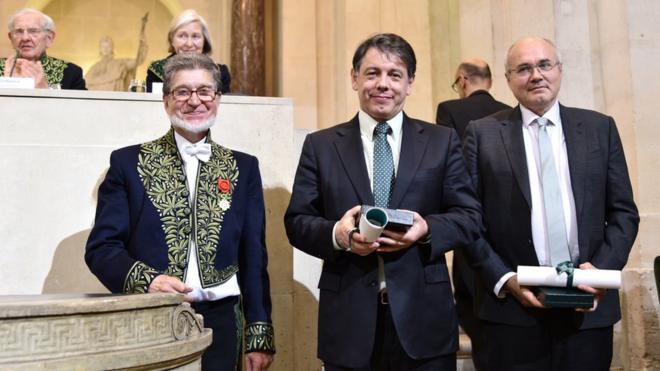Marcelo Viana é o do meio, à direita dele, também de terno, é o francês com quem ele divide o prêmio, e à esquerda é um membro da Academia de Ciências da França.