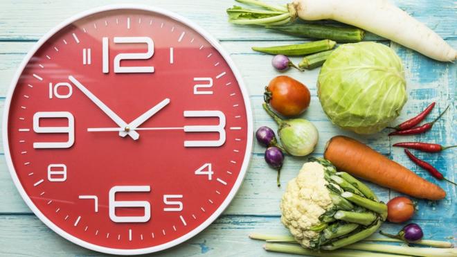 Reloj grande junto a verduras