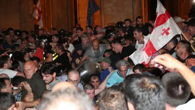 Policemen attempt to block protesters during a rally against the visit of the Russian delegation