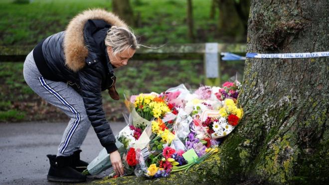 Женщина кладет цветы на месте убийства Джоди Чесни