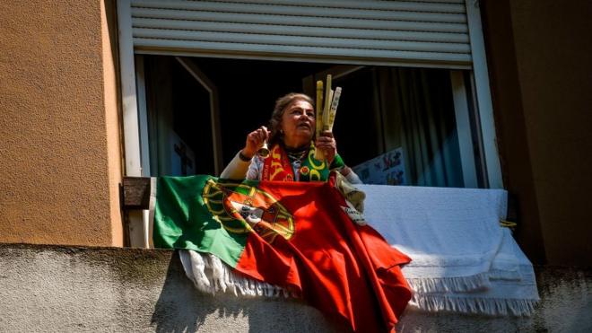 Mujer con la bandera de Portugal en la ventana.