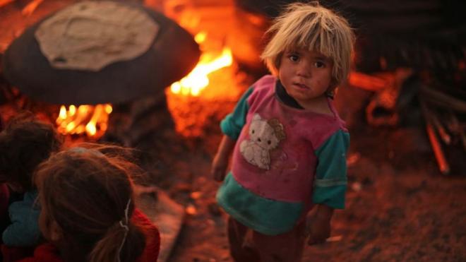 Un niño sirio mira a la cámara en un campo de refugiados.