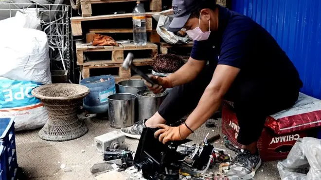 विद्युतिय फोहोरबाट धातु निकाल्दै एक मजदुर।