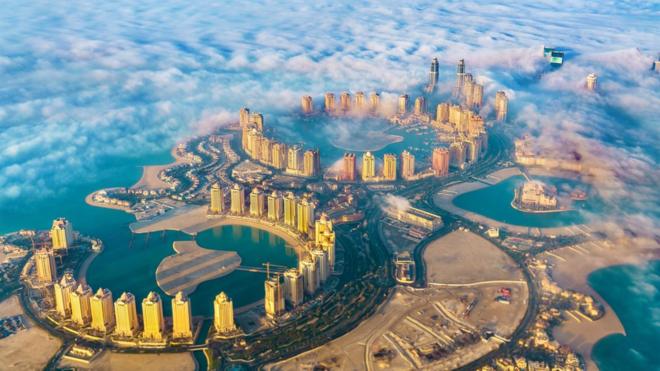 Fotografia colorida mostra vista aérea300 bonus betanouma ilha com três baías e muitos prédios altos