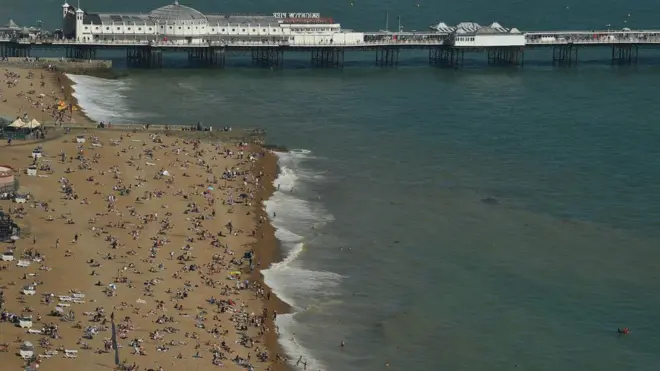 د برتانیا برایټون کې ځايي اوسېدونکي د لمر له شدته د ځان ژغورنې لپاره د سمندر غاړې ته وتلي