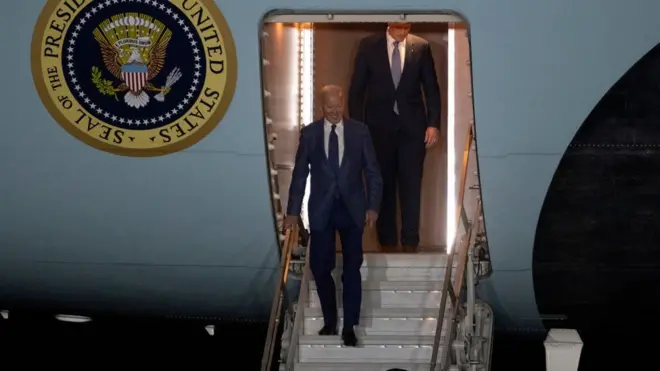 الرئيس الأمريكي جو بايدن يبتسم وهو ينزل سلم طائرة الرئاسة في 11 أبريل/نيسان 2023 في أيرلندا الشمالية