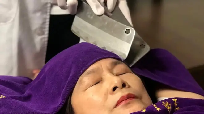 Женщине делают массаж огромными ножами