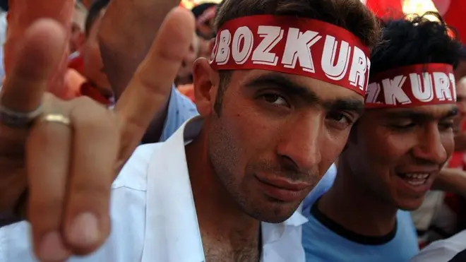 Pozdrav na fotografiji je simbol Sivih vukova, koji prikazuje glavu vuka. Kažiprst i mali prst formiraju uši, palac, srednji i domali prst formiraju nos i usta.