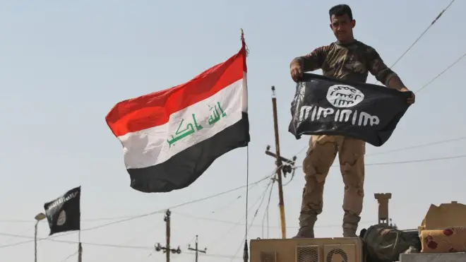 Iraqi soldier dey hold IS flag upside-down