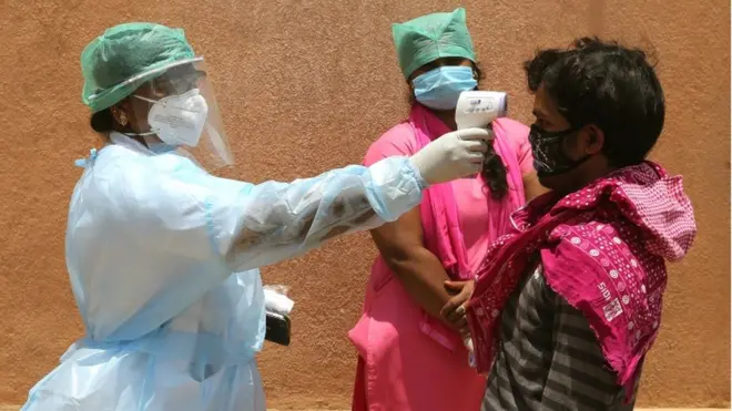 Petugas kesehatan memeriksa suhu tubuh seorang warga di Bangalore, India, 9 Mei lalu.