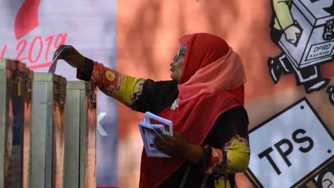 A woman casts her ballot in Indonesia in a pre-election drill