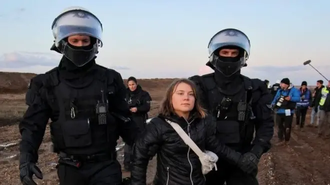 Greta Thunberg held by police officers at climate protest