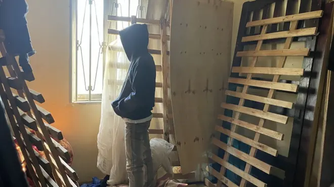 شاب لا يظهر وجهه ينظر من النافذة.