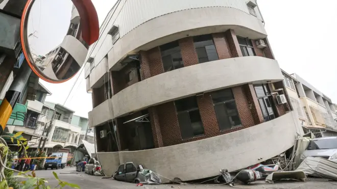 Crushed vehicles are seen under a building that was damaged after a powerful earthquake hit Tainan