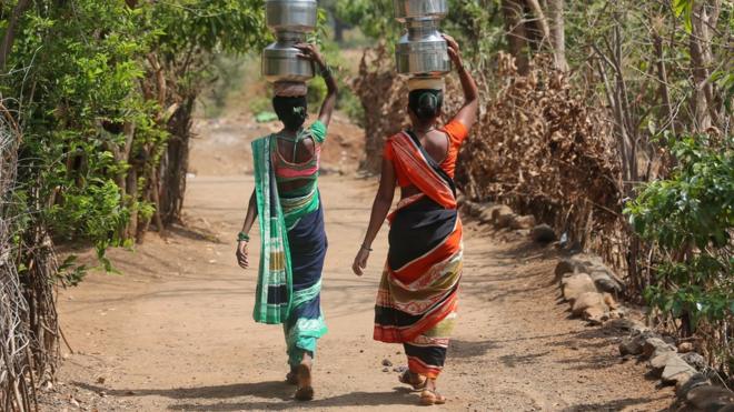 Women carry pitchers after filling them with water from a hand pump to their houses in Thane district in the western state of Maharashtra, India, May 30, 2019