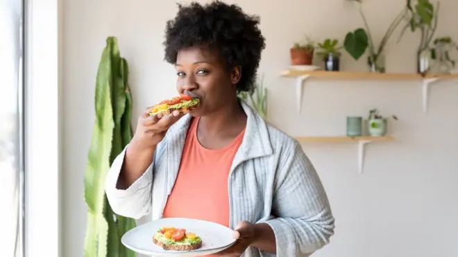 Une femme prend son petit-déjeuner à la maison.