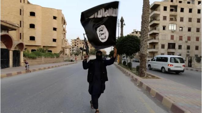 أحد أعضاء تنظيم الدولة الإسلامية في سوريا يلوح بعلم التنظيم عام 2014