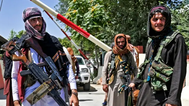Taliban fighters with weapons stand guard along a roadside near the Zanbaq Square in Kabul on 16 August