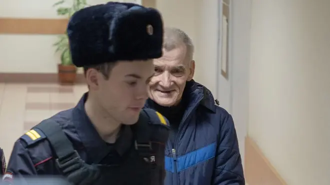 Yury Dmitriev es escoltado por un policía ruso en el tribunal.