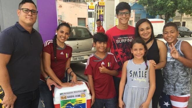 A família venezuelana reunida vendendo com a ajuda de dois brasileiros, os irmãos Thaynara e Thiago