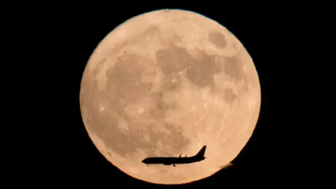 A plan flies across the moon - seen from Beijing, China