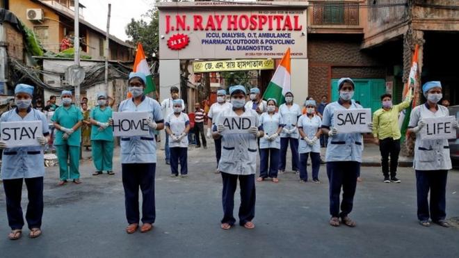 Medical staff members hold placards as they stand outside a hospital to show solidarity with people who are affected by the coronavirus disease (COVID-19), and with doctors, nurses and other healthcare workers from all over the world during a 21-day nationwide lockdown to slow the spreading of the disease, in Kolkata, India, April 5, 2020.