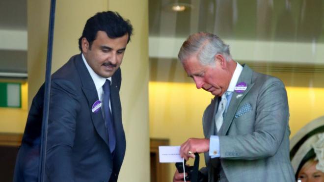 Fotografia colorida de tamim bin Hamad al Thani, um homem de feições árabes e bigode e de meia idade, e Charles, um homem branco idoso de cabelo branco; ambos usam ternos