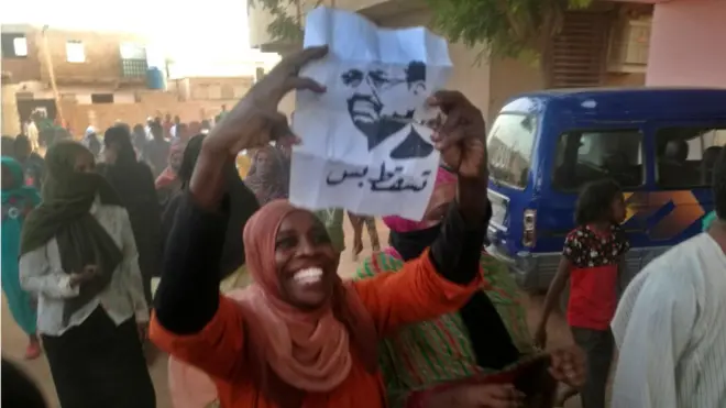 متظاهرة ترفع صورة الرئيس السوداني عمر البشير مع عبارة "تسقط بس" خلال مظاهرة في الخرطوم يوم الثامن من فبراير 2019