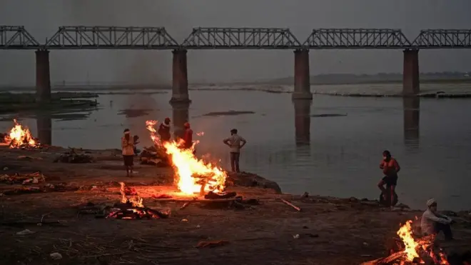Funeral pyres are lit by the Ganges in Allahabad, where bodies have been washing downstream for days