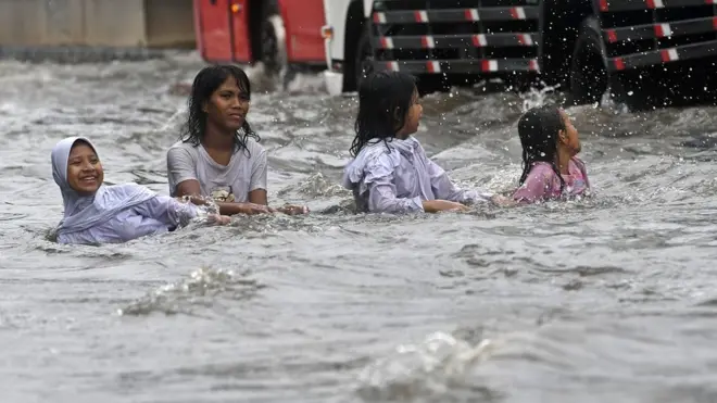 Sejumlah anak bermain air yang membanjiri Jalan Gunung Sahari di Pademangan, Jakarta, Jumat (24/01).