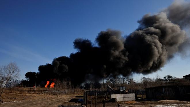 Una columna de humo se eleva desde tanques de combustible en llamas que, según los locales, fueron alcanzados por cinco cohetes en la base aérea de Vasylkiv, en las afueras de Kiev este 12 de marzo.