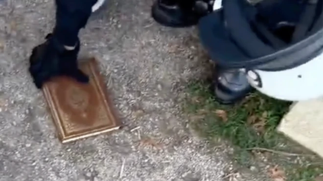 بخشی از تصویر امروز از دو مهاجر عراقی که ابتدا نسخه‌ای از قرآن را لگدمال کردند و سپس آن را به آتش کشیدند