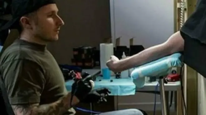 سکاٹ کیمبل اپنے بازو کو فنکارانہ تجربے کے لیے پیش کرنے والے رضاکار کا مفت ٹیٹو بناتے ہیں