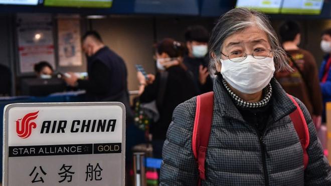An Air China passenger wearing a respiratory mask walks after checking in on January 31, 2020