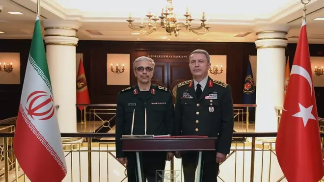 رئيس أركان الجيش الإيراني ونظيره التركي يقفان وعلى جانب كل منهما علم بلاده