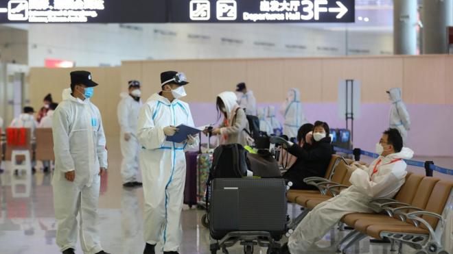 A staff member wearing a protective suit talks with an inbound passenger at Nanjing Lukou International Airport amid the coronavirus outbreak on March 16, 2020 in Nanjing, Jiangsu Province of China.