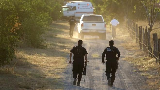 Dos policías corren a la escena del crimen en Colima.