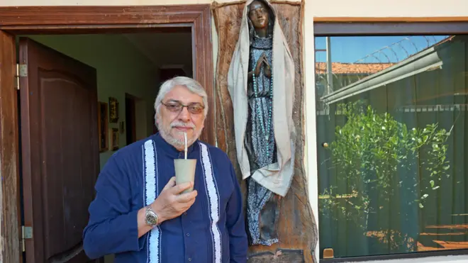 Tomando tereré, con una virgen en la puerta de su casa. Así recibió Lugo a BBC Mundo.