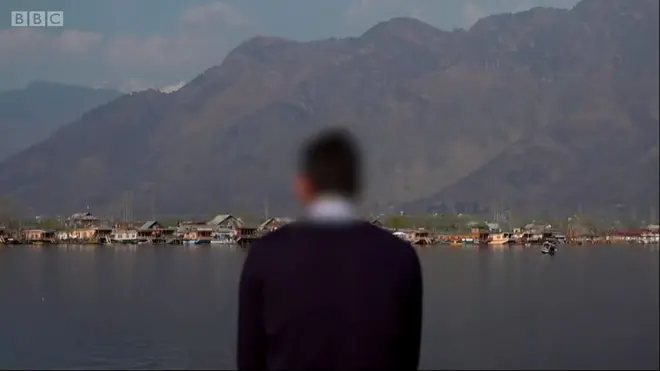 ผู้ชายยืนหันหลัง พื้นหลังเป็นภูเขาและทะเลสาบ