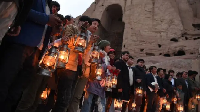 People holding lanterns stand beside the cliff